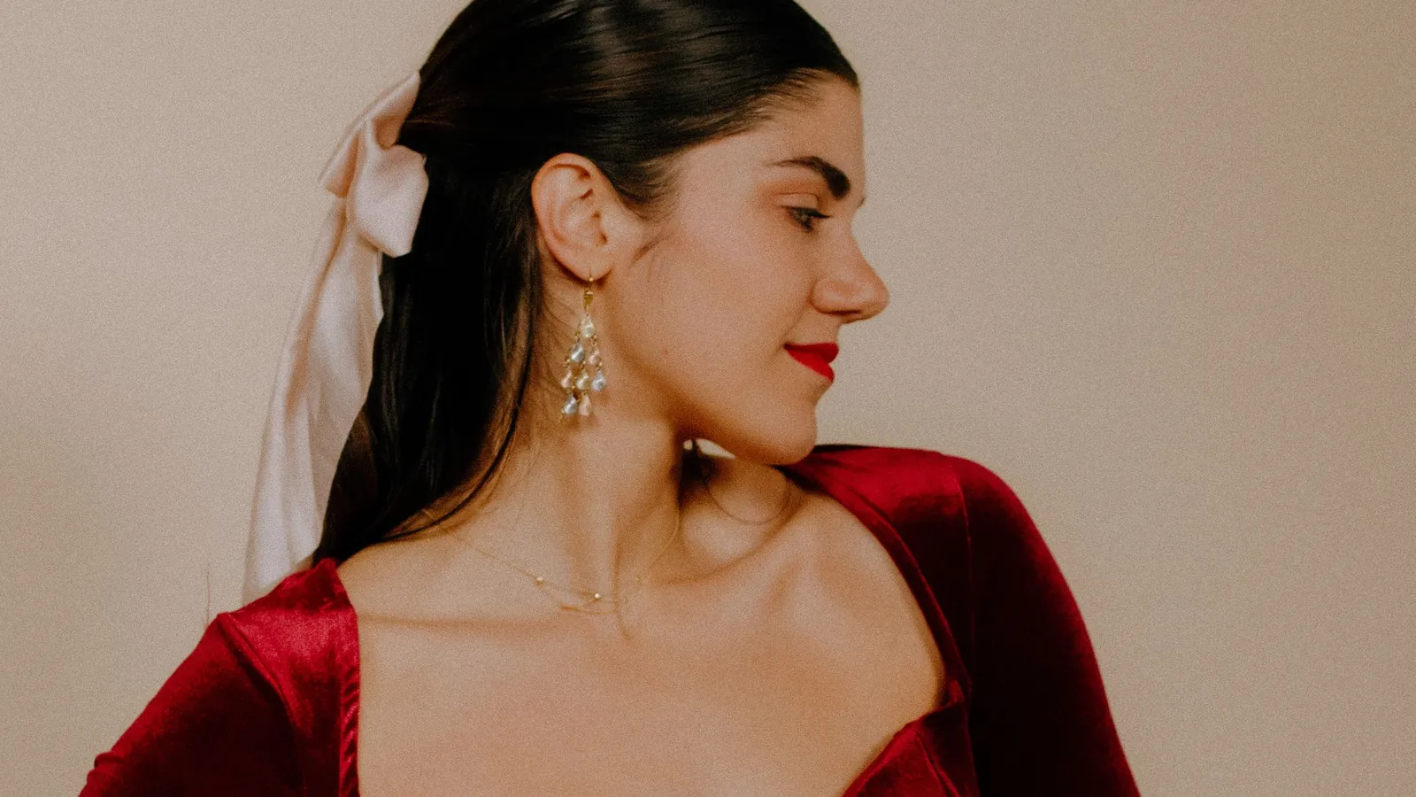 Model in a deep burgundy velvet dress with a sweetheart neckline and statement earrings in a studio