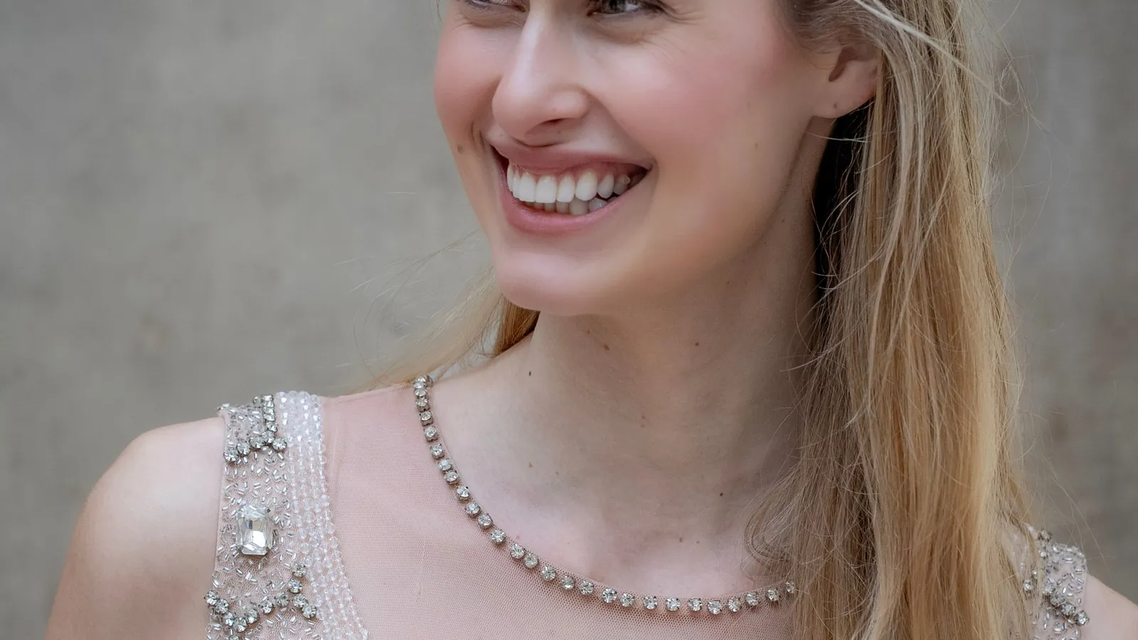 Smiling model in an intricately beaded, Art Deco-style embellished dress against a neutral background in Milan